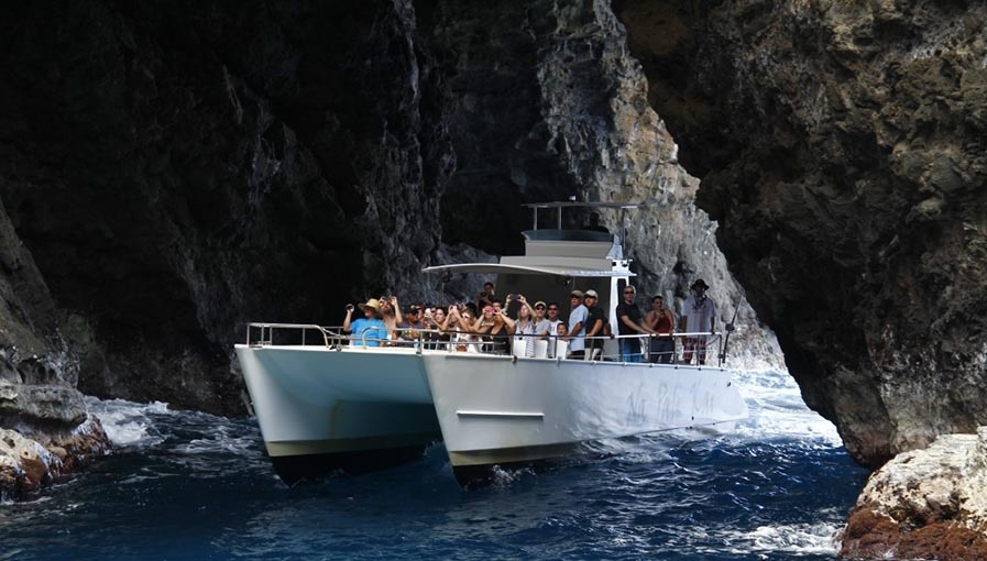 Na Pali Kai boat tour entering a Kauai sea cave, passengers enjoying the view.