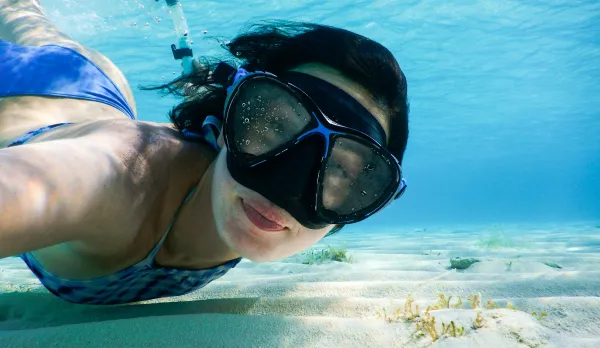 A close-up of a snorkeler wearing a dive mask in clear blue water during a Kauai snorkeling tour with Makana Charters.
